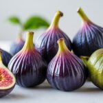 Fruta fresca e vibrante começando com a letra V sobre uma superfície branca, destacando suas cores e texturas.